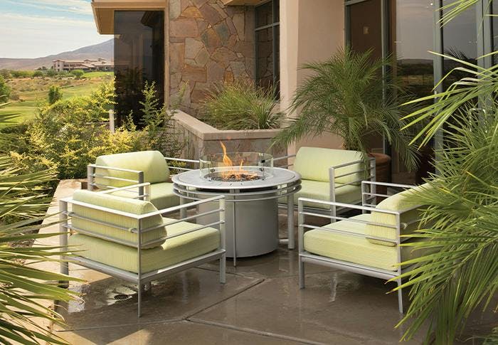 lounge chairs with green cushions around a fire table